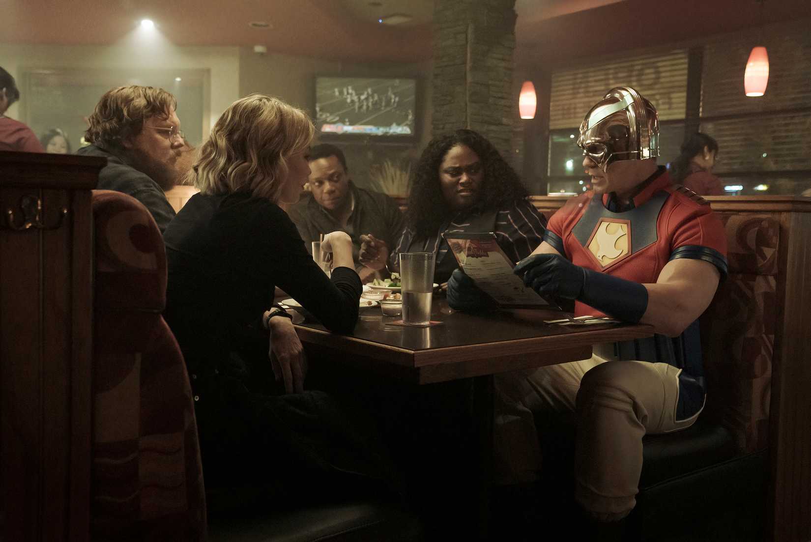 Toda a equipe de pacificador sentado em um estande em um restaurante familiar em um imóvel do episódio 1