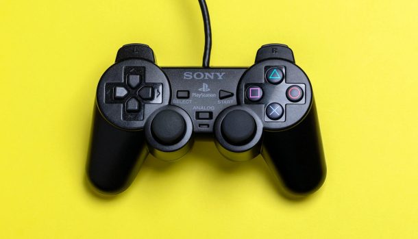 A close-up view of a black gaming controller set against a vibrant yellow background, highlighting modern gaming technology.