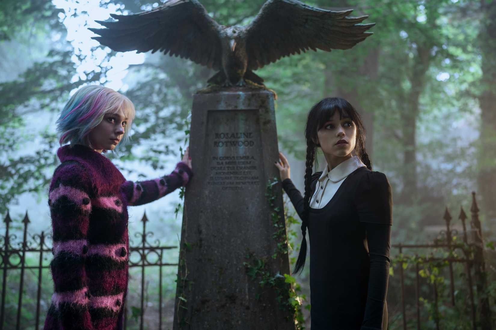 Imagem da segunda temporada de quarta -feira. Enid e quarta -feira colocam a mão sobre o que uma lápide.