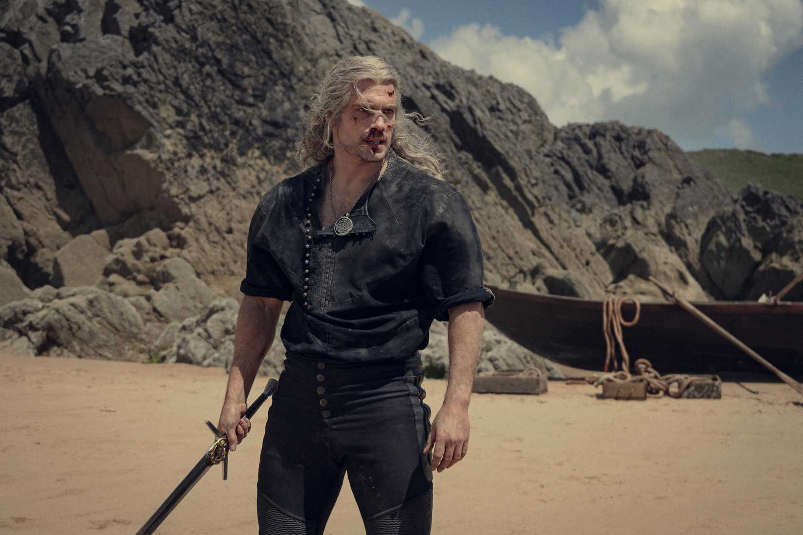 Geralt fica em uma praia com o nariz ensanguentado e sua espada mantida ao seu lado na terceira temporada de Witcher