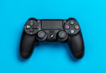 Black game controller against a vibrant blue background, perfect for gaming-themed content.