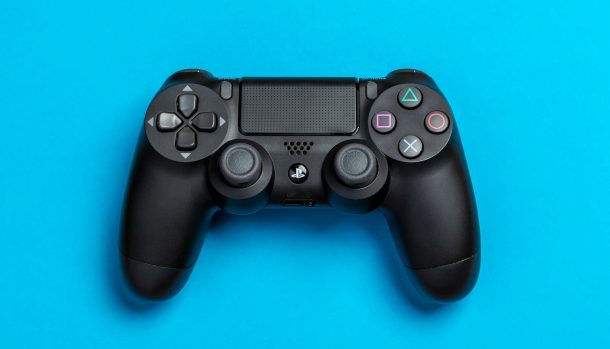 Black game controller against a vibrant blue background, perfect for gaming-themed content.