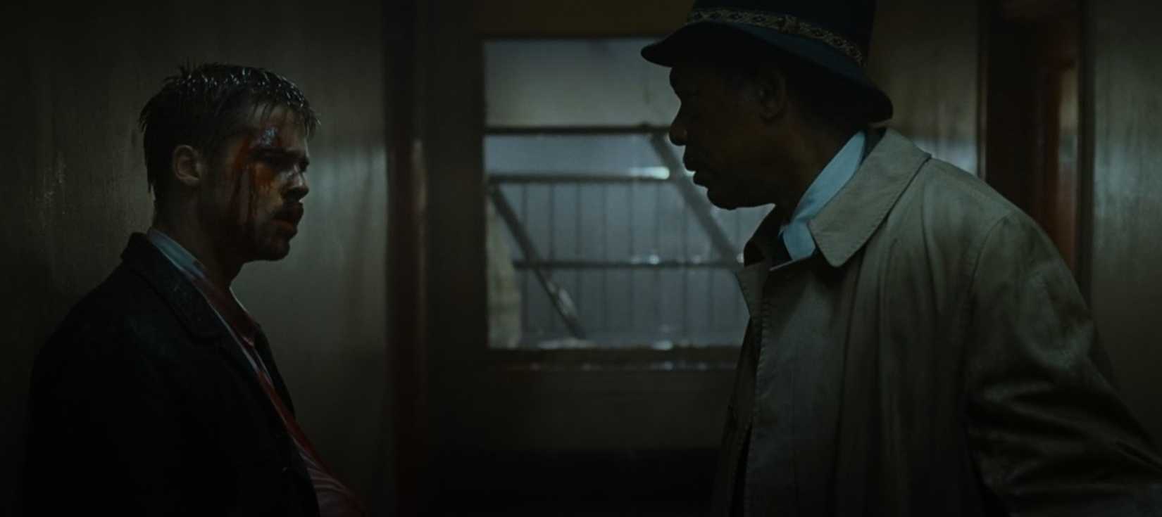 Brad Pitt e Morgan Freeman discutem em um corredor caracteristicamente sombrio em uma cena do filme sete