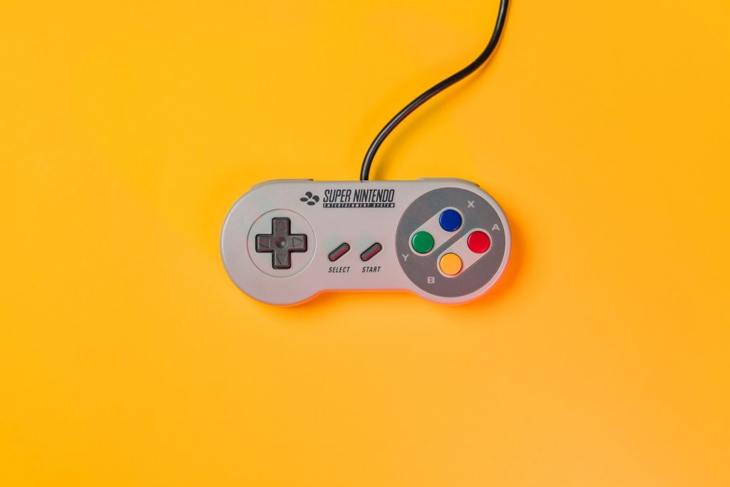 white nintendo game controller on yellow surface