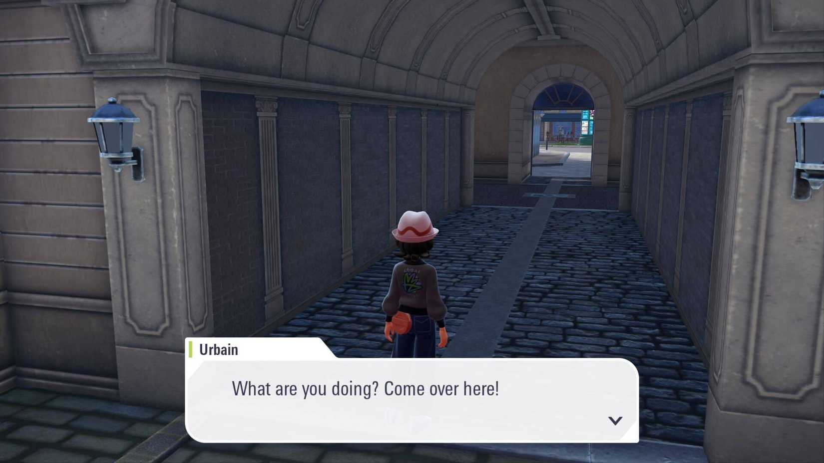 Andando por um beco em Pokémon Legends: ZA, mas uma janela de diálogo aparece com Urbain me dizendo para me virar.
