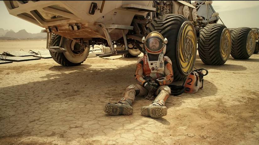 Matt Damon em Mark Watney se inclina contra um rover de Marte no marciano