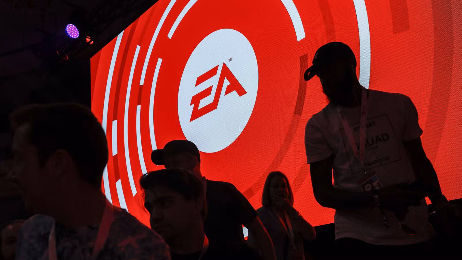 As silhuetas dos participantes são vistas em frente ao logotipo da Electronic Arts Inc.