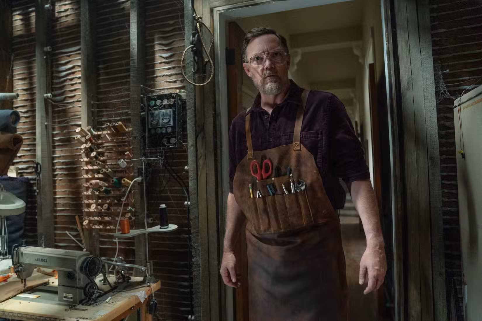 Matthew Lillard em Five Nights at Freddy's 2, parado em uma porta vestindo um avental de couro cheio de ferramentas