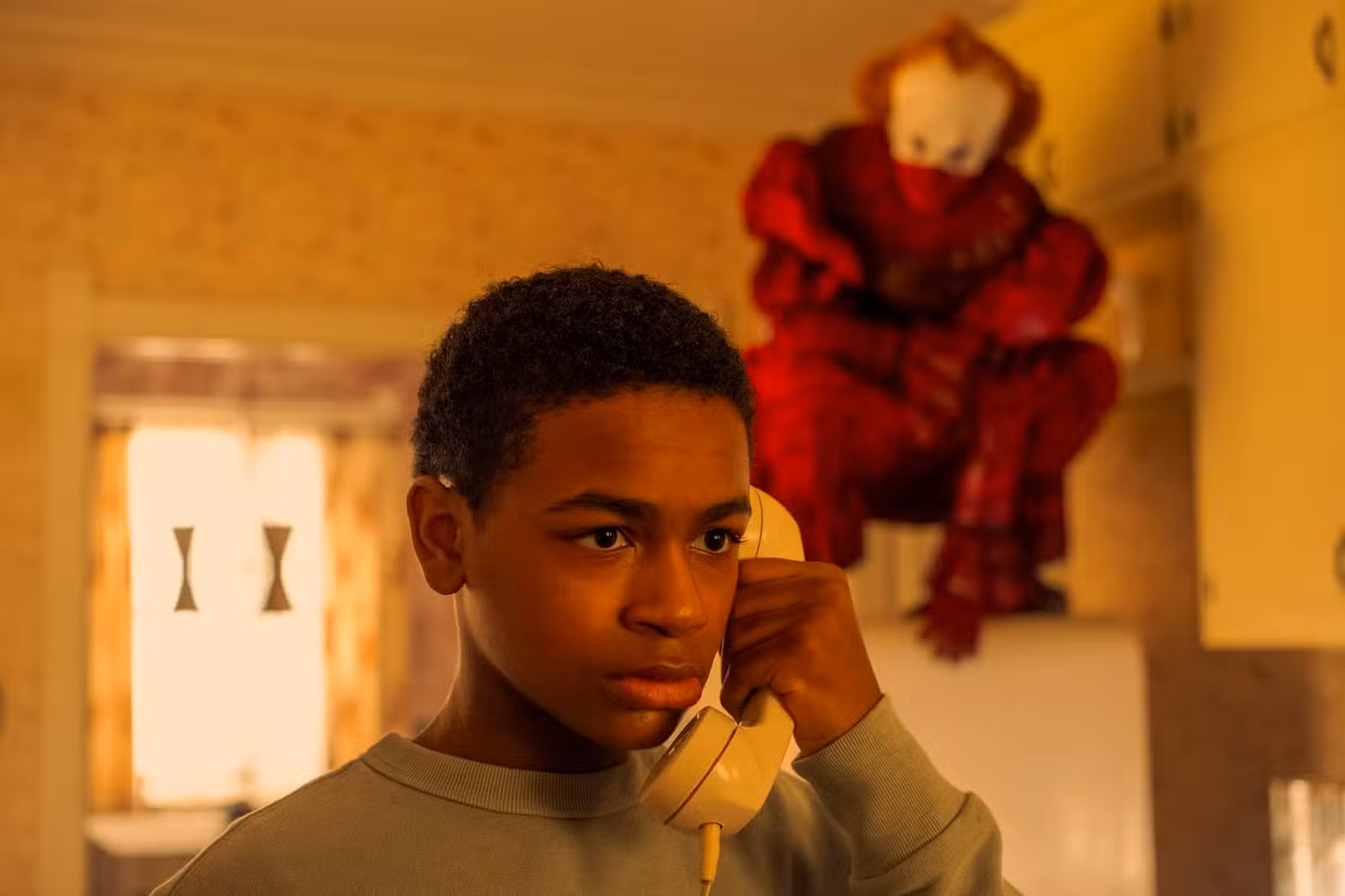 Will Hanlon (Blake Cameron James) ao telefone, enquanto Pennywise-(Bill Skarsgard) o persegue em Welcome to Derry