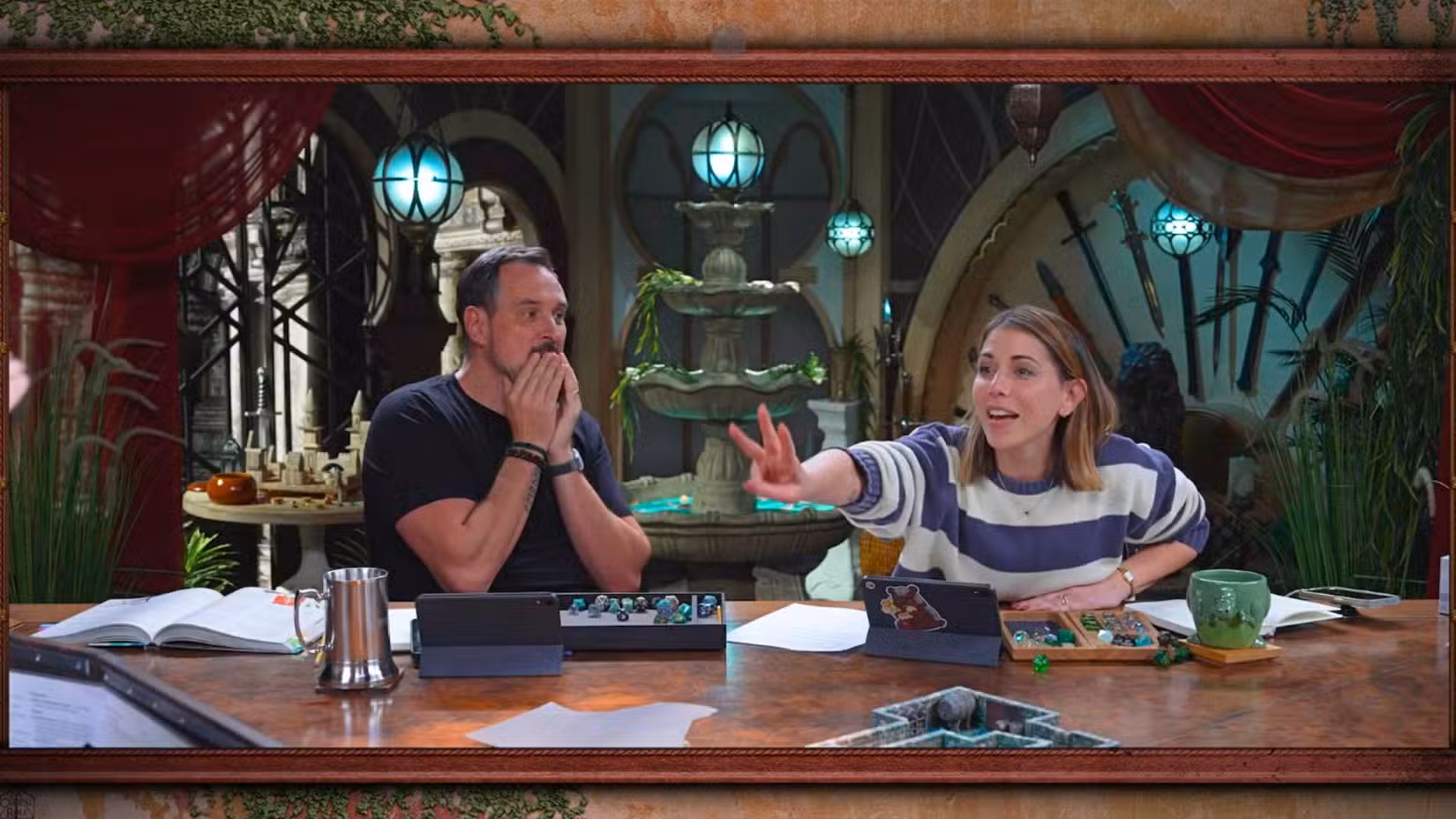 Uma imagem do Critical Role Campaign 4, Episódio 10. Apresenta Travis Willingham, com as mãos cobrindo o rosto em estado de choque. Ao lado dele está Laura Bailey, que aponta três dedos para Brennan fora da tela. 