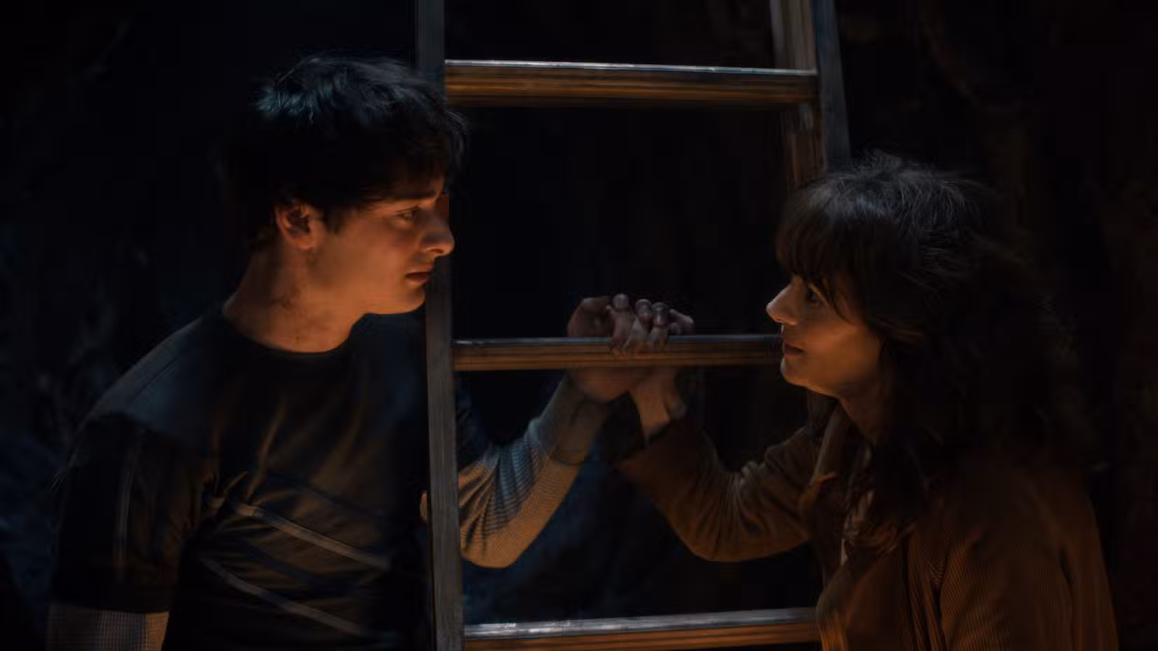 Will Byers (Noah Schnapp) conversa com sua mãe, Joyce Byers (Winona Rider) enquanto segura os degraus de uma escada na 5ª temporada de Stranger Things