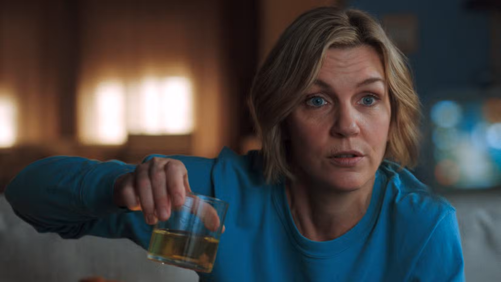 A protagonista do Pluribus, Carol Sturka, segura um copo com um líquido amarelo e transparente, que o show mostra "pessoas do pod" tenho bebido sem parar.