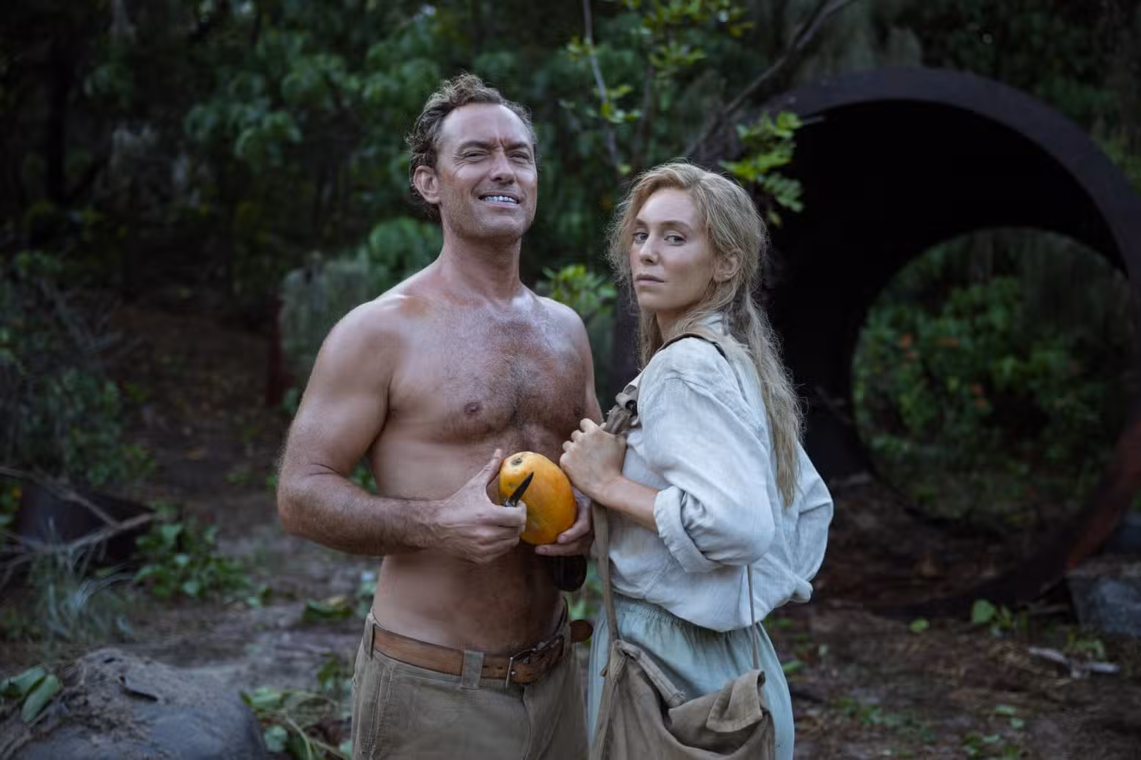 Jude Law sorrindo com dentes de prata falsos e Vanessa Kirby rosnando para a câmera no Éden