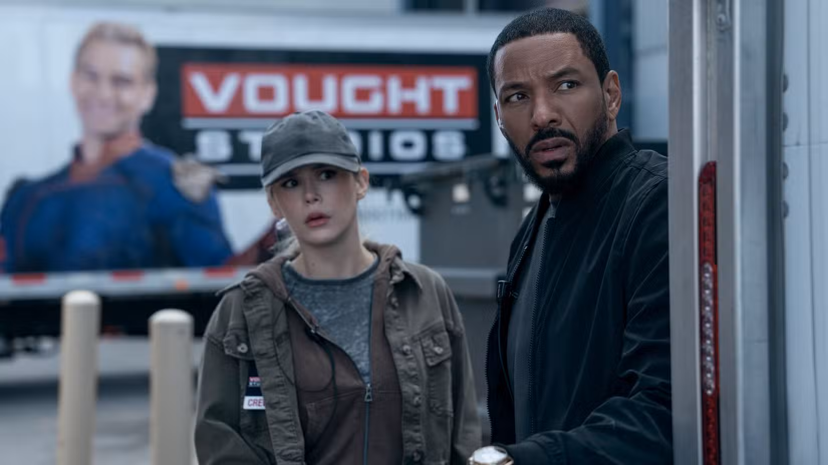 Annie January, também conhecida como Starlight (Erin Moriarty), se esconde ao lado de Mother's Milk (Laz Alonso) em frente a um outdoor do Vough Studios representando Homelander na 5ª temporada de The Boys