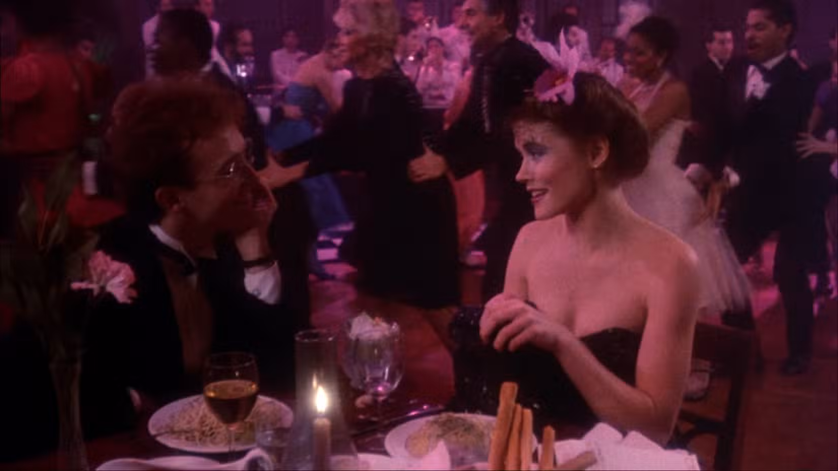 Victor (Reed Birney) está sentado em frente à sua paixão Nancy (Sheree J. Wilson) em uma mesa de jantar em uma antiga boate de big band com iluminação rosa, com clientes cantando uma fila de conga ao fundo.