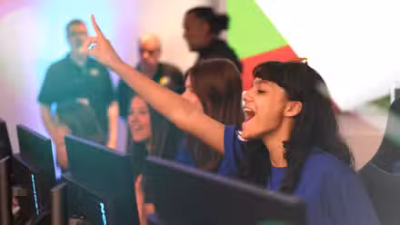 Uma adolescente de camisa azul faz a contagem regressiva, levantando um dedo com entusiasmo.