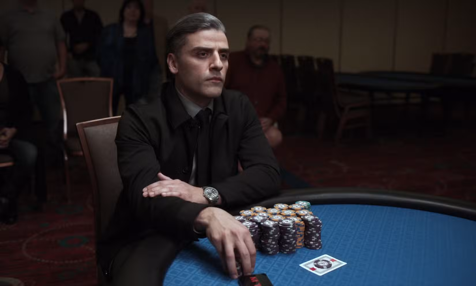 Oscar Isaac em The Card Counter segurando suas fichas na mesa de pôquer