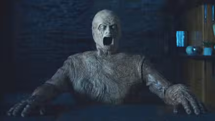 Um golem horrível posou sentado em uma mesa com a boca aberta em Oddity