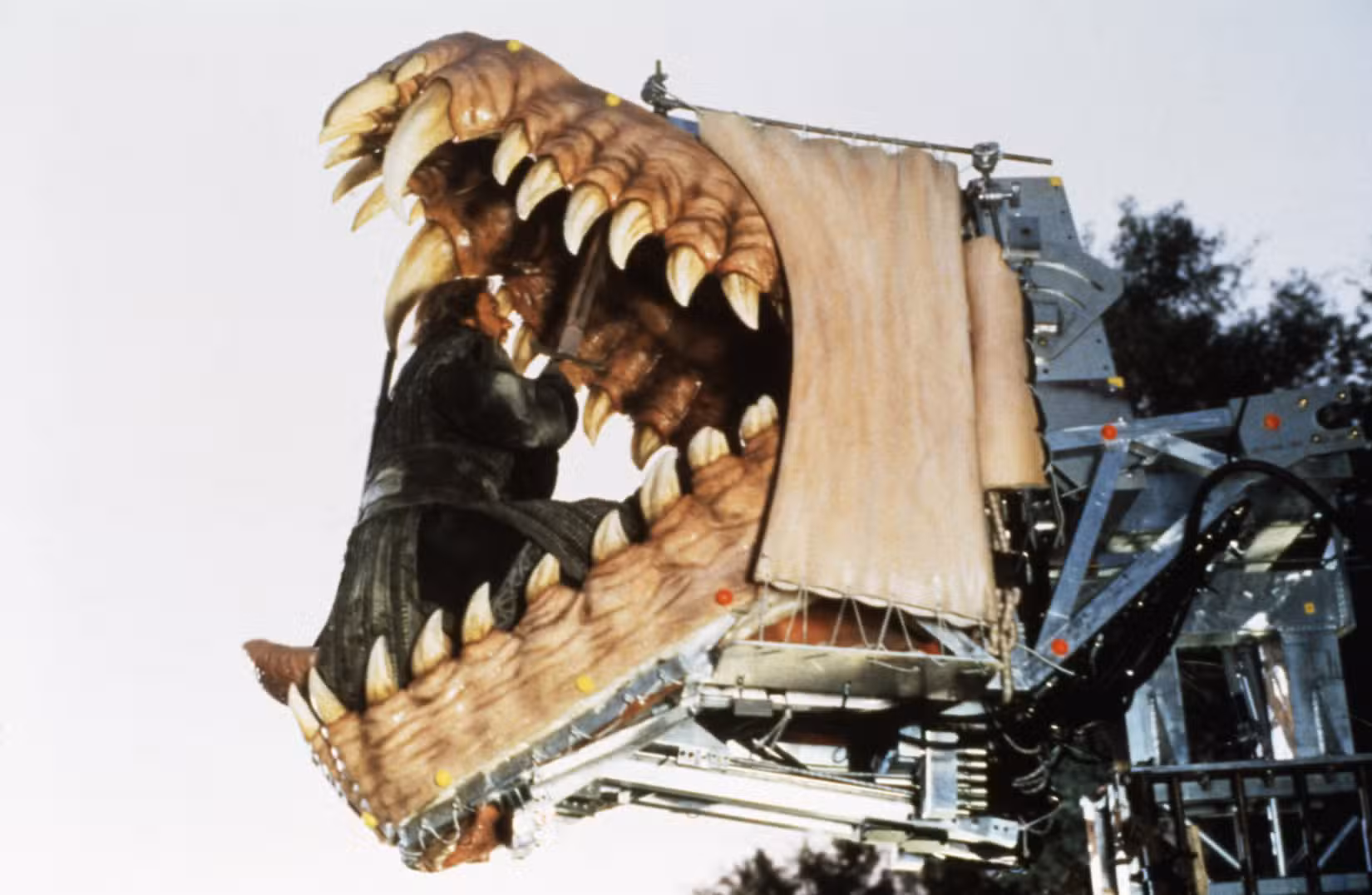 Uma imagem dos bastidores de Bowen de Dragonheart 1996. Mostra Quaid, como Bowen, sentado dentro de uma cabeça de dragão animatrônico.