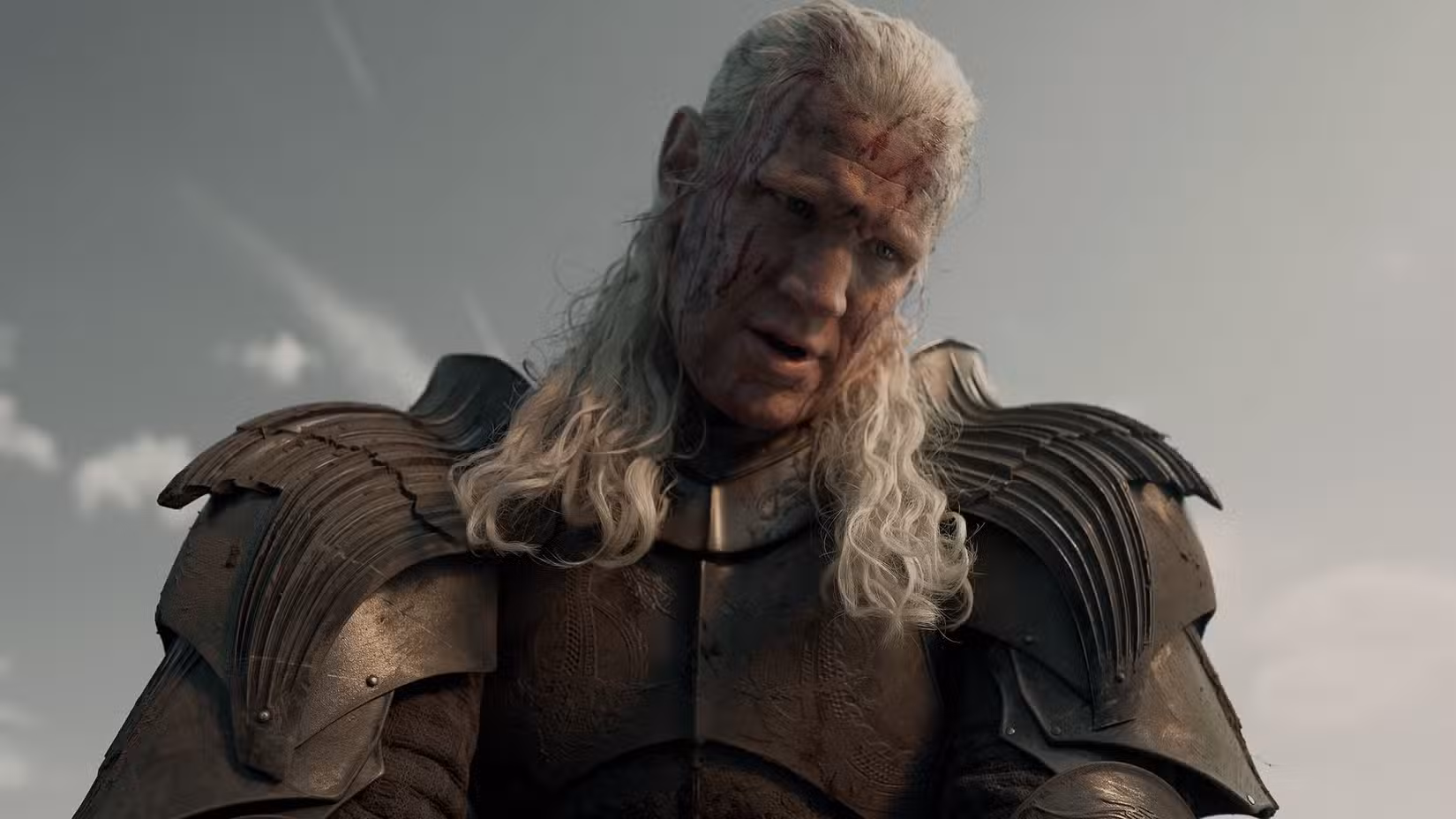Daemon Targaryen (Matt Smith) usa armadura e olha para baixo com o rosto manchado de sangue na 3ª temporada de House of the Dragon.