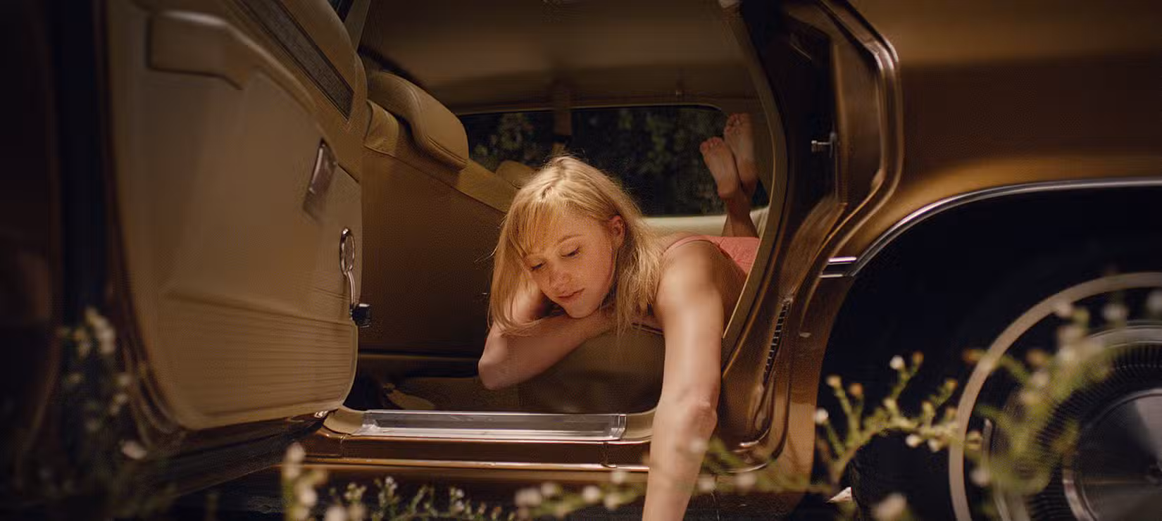 Maika Monroe inclinando-se para fora de um carro em It Follows