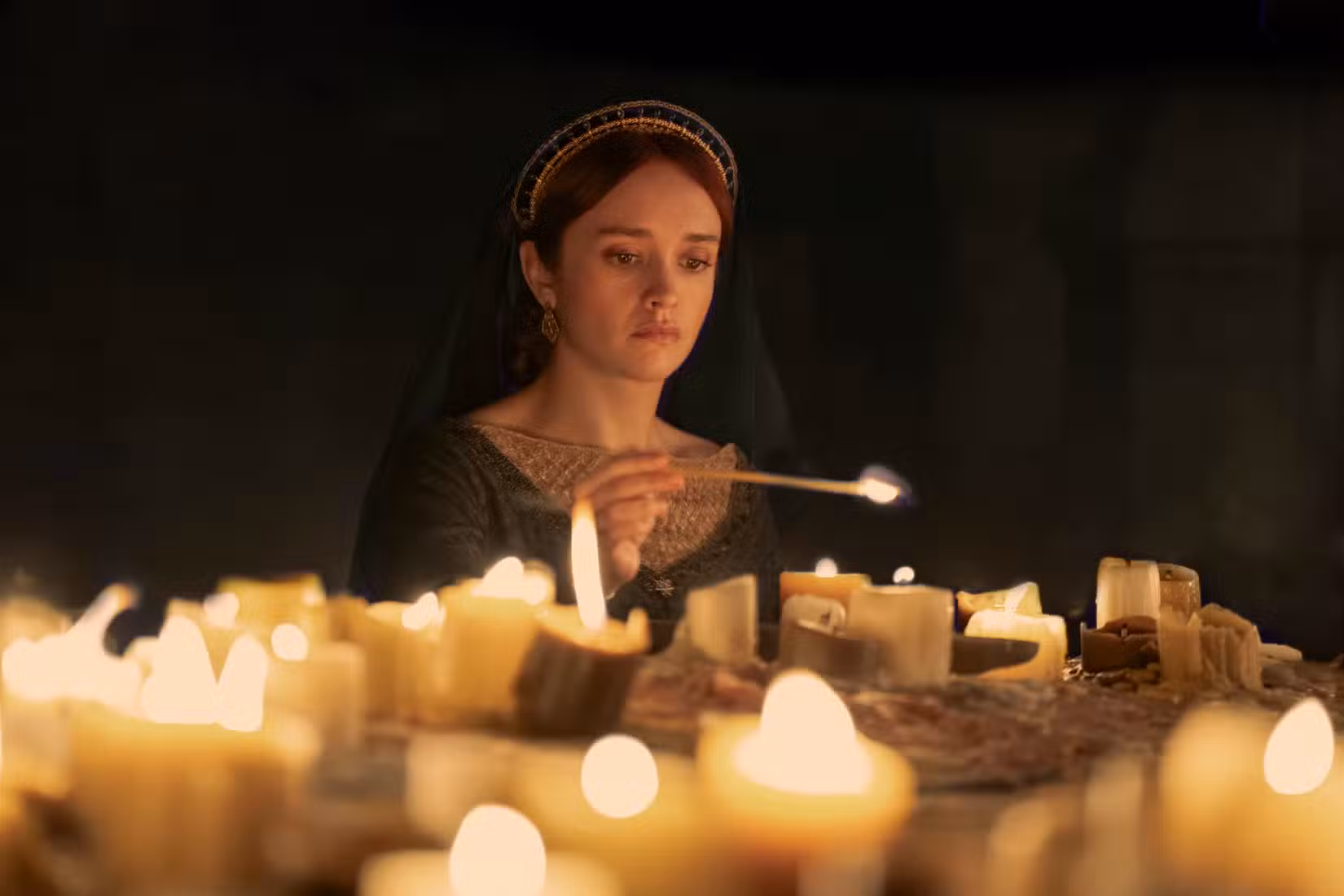 Alicent acende um bando de velas em um quarto escuro na 2ª temporada de House of the Dragon