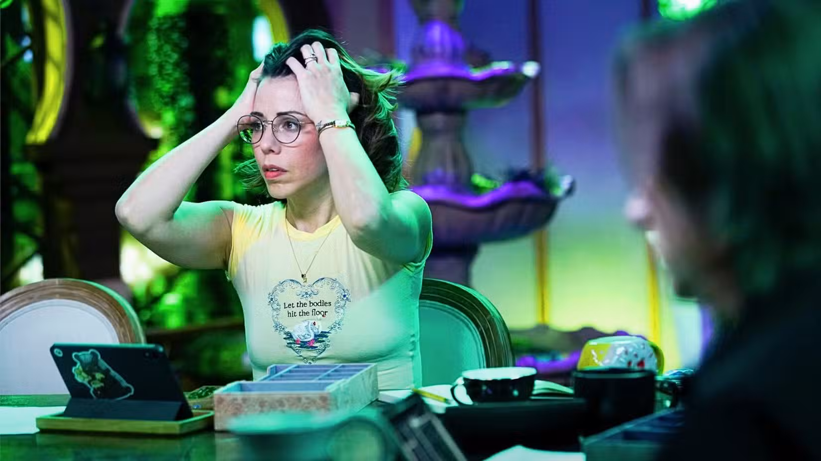 Laura Bailey, da Critical Role, está sentada a uma mesa. Ela parece visivelmente estressada.
