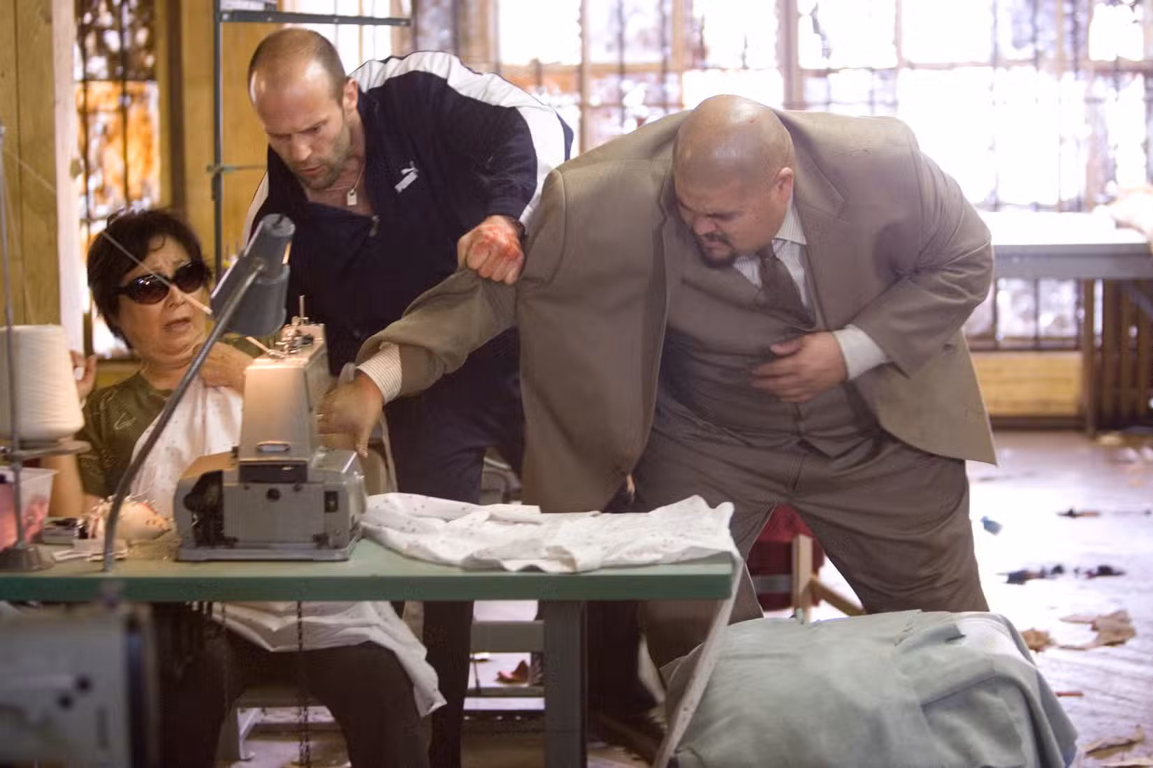 Chev Chelios coloca a mão de um capanga em uma máquina de costura em Crank (2006)