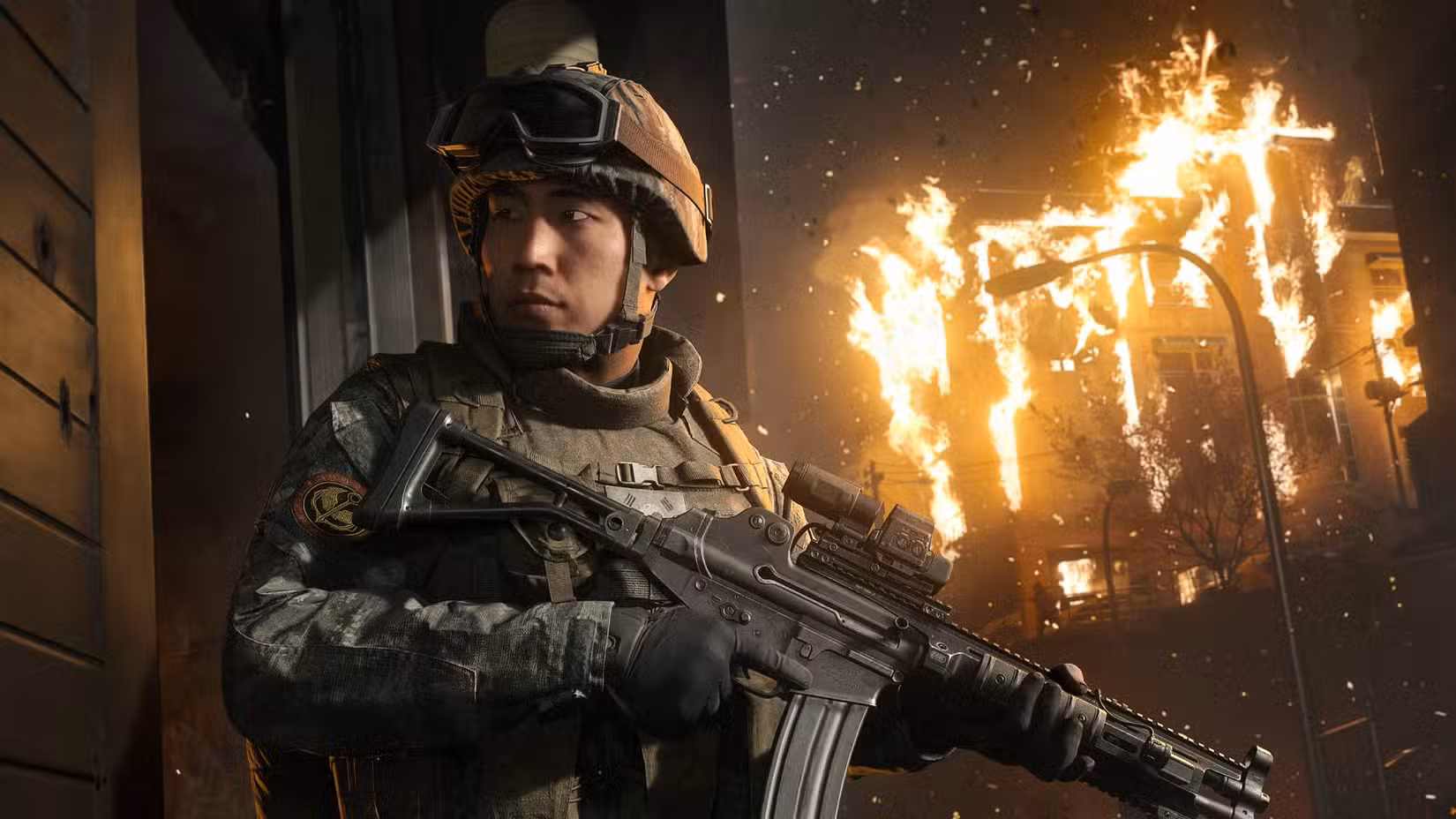 Um soldado em Modern Warfare 4 olhando para trás enquanto segura um rifle de assalto com um prédio em chamas ao fundo.