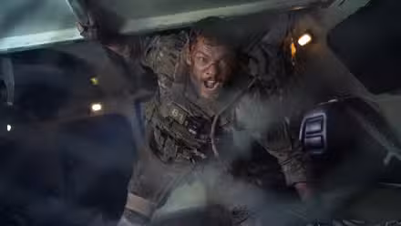 81 (Alan Ritchson) grita dentro de um transporte blindado em uma cena do filme War Machine da Netflix
