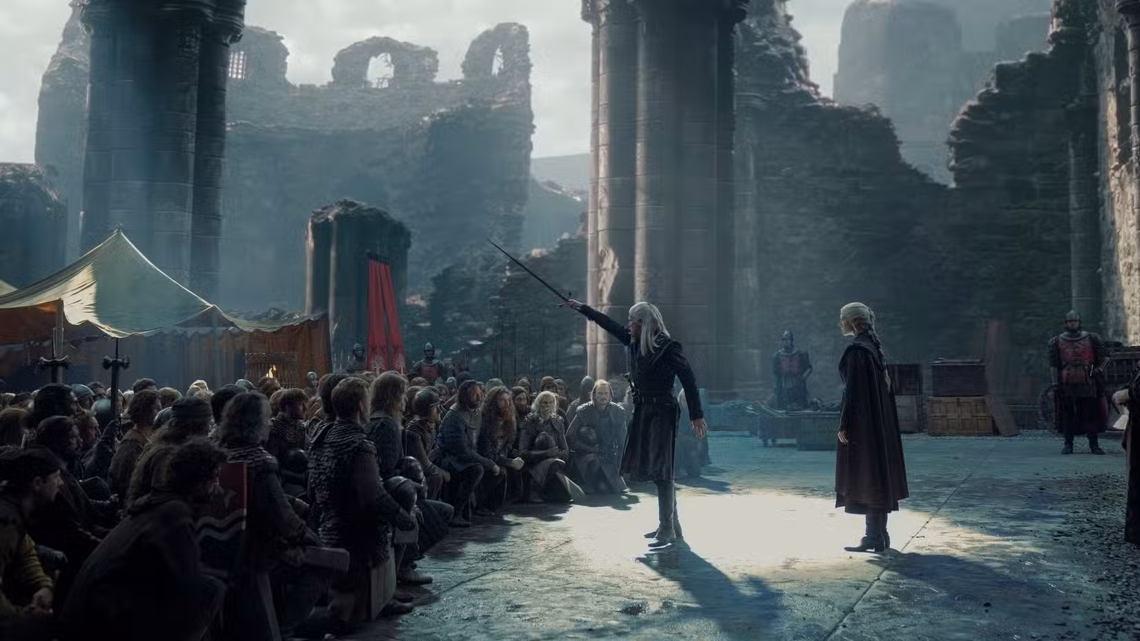 Daemon Targaryen (Matt Smith) segura uma espada na frente de uma multidão ajoelhada enquanto Rhaenyra (Emma D'Arcy) está atrás dele na 2ª temporada de House of the Dragon.