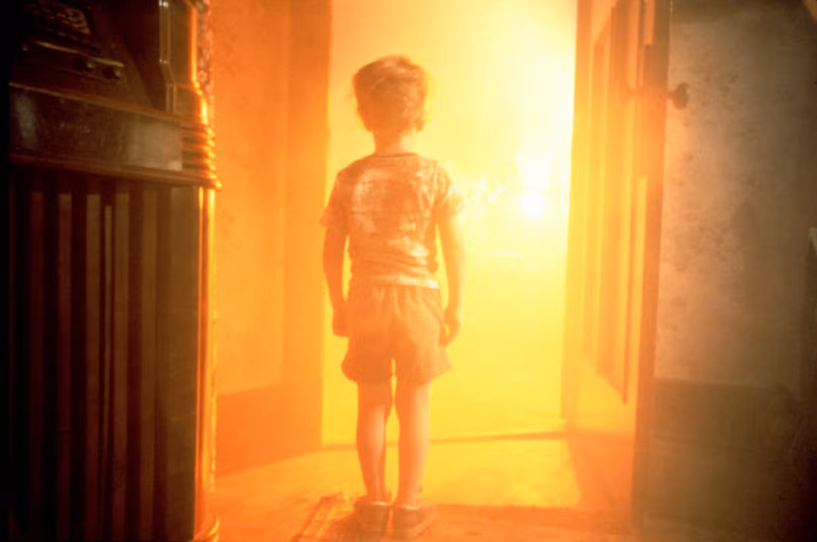 Um garotinho fica na frente de uma luz amarela brilhante
