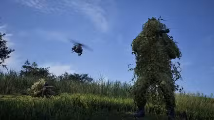 Dois soldados em trajes ghillie em um campo enquanto um helicóptero voa acima deles em Wardogs.