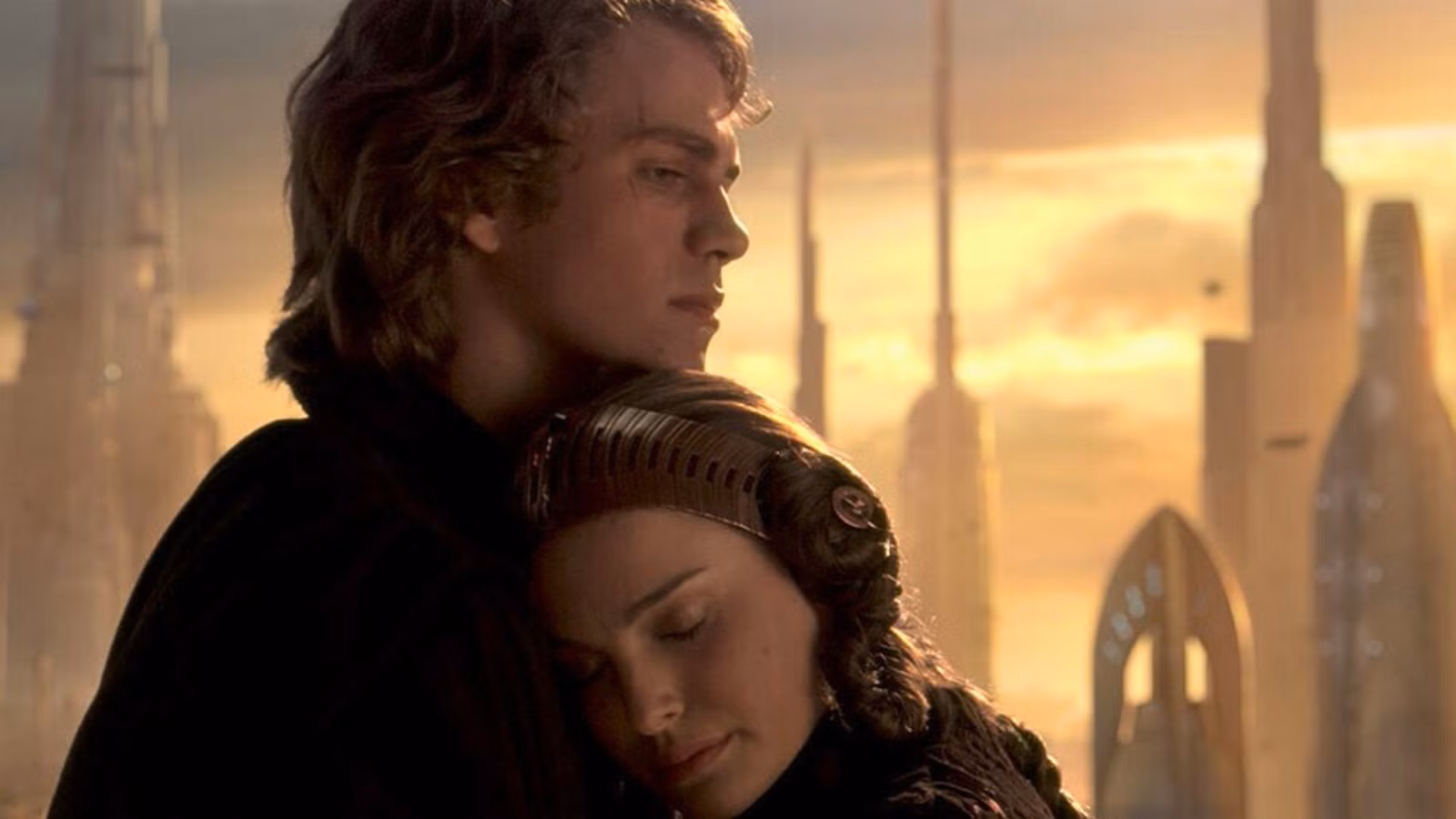 Uma imagem de Anakin Skywalker e Padme Amidala de Star Wars: A Vingança dos Sith. Mostra Padme, com o cabelo preso e usando uma bandana de ficção científica, inclinando-se para Anakin. Anakin tinha cabelos castanhos que terminavam acima dos ombros. Ele tem uma cicatriz no olho direito e uma expressão pensativa no rosto.