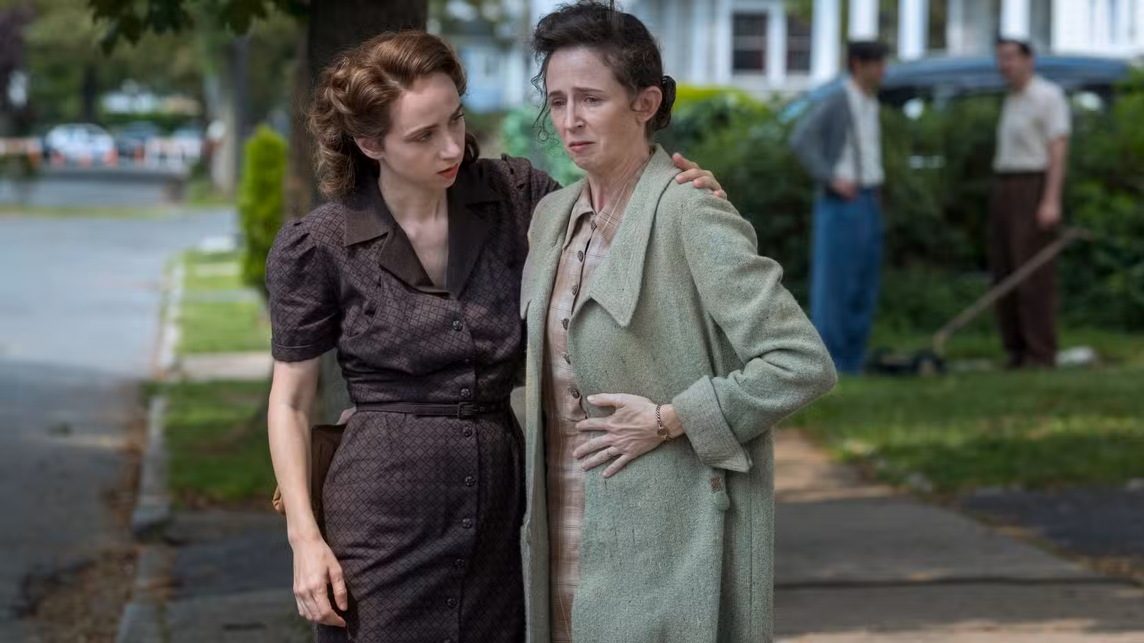 Bess Levin (Zoe Kazan) conforta Selma Wishnow (Kristen Sieh), que parece à beira das lágrimas enquanto estão em um gramado suburbano em The Plot Against America.