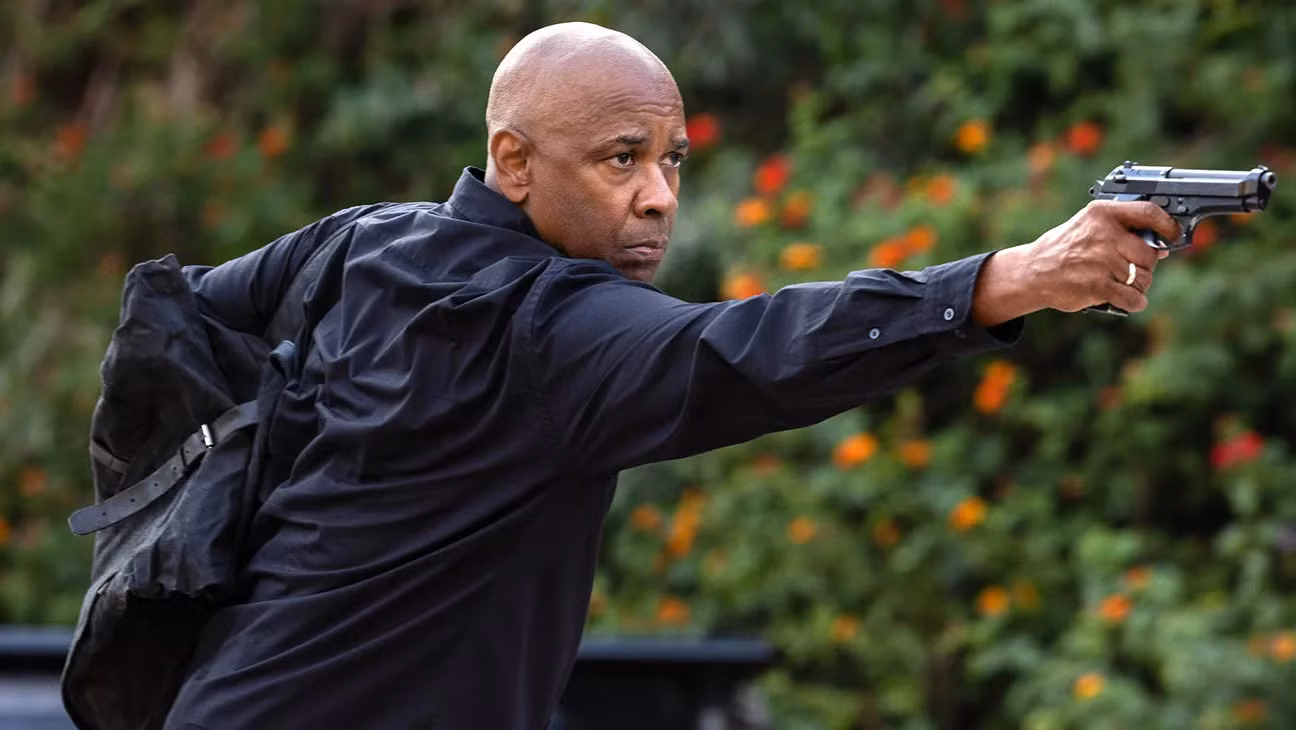Denzel Washington apontando uma pistola e segurando uma bolsa preta em The Equalizer 3.