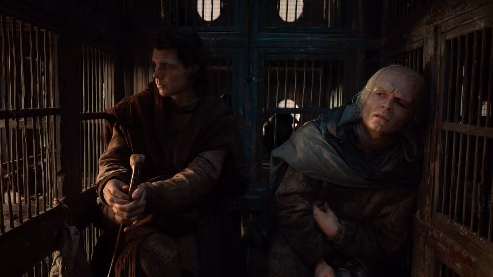 Larys Strong (Matthew Needham) e King Aemond (Tom Glynn-Carney) sentam-se na parte de trás de uma carruagem cheia de gaiolas de pássaros na 3ª temporada de House of the Dragon