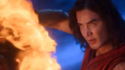 Liu Kang (Ludi Lin, um homem de cabelos compridos e uma túnica vermelha, parece feroz enquanto atira fogo em Mortal Kombat 2